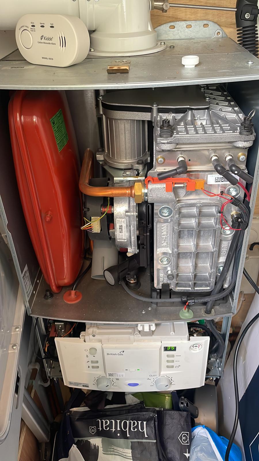 Boiler servicing with carbon monoxide alarm mounted above for gas safety compliance