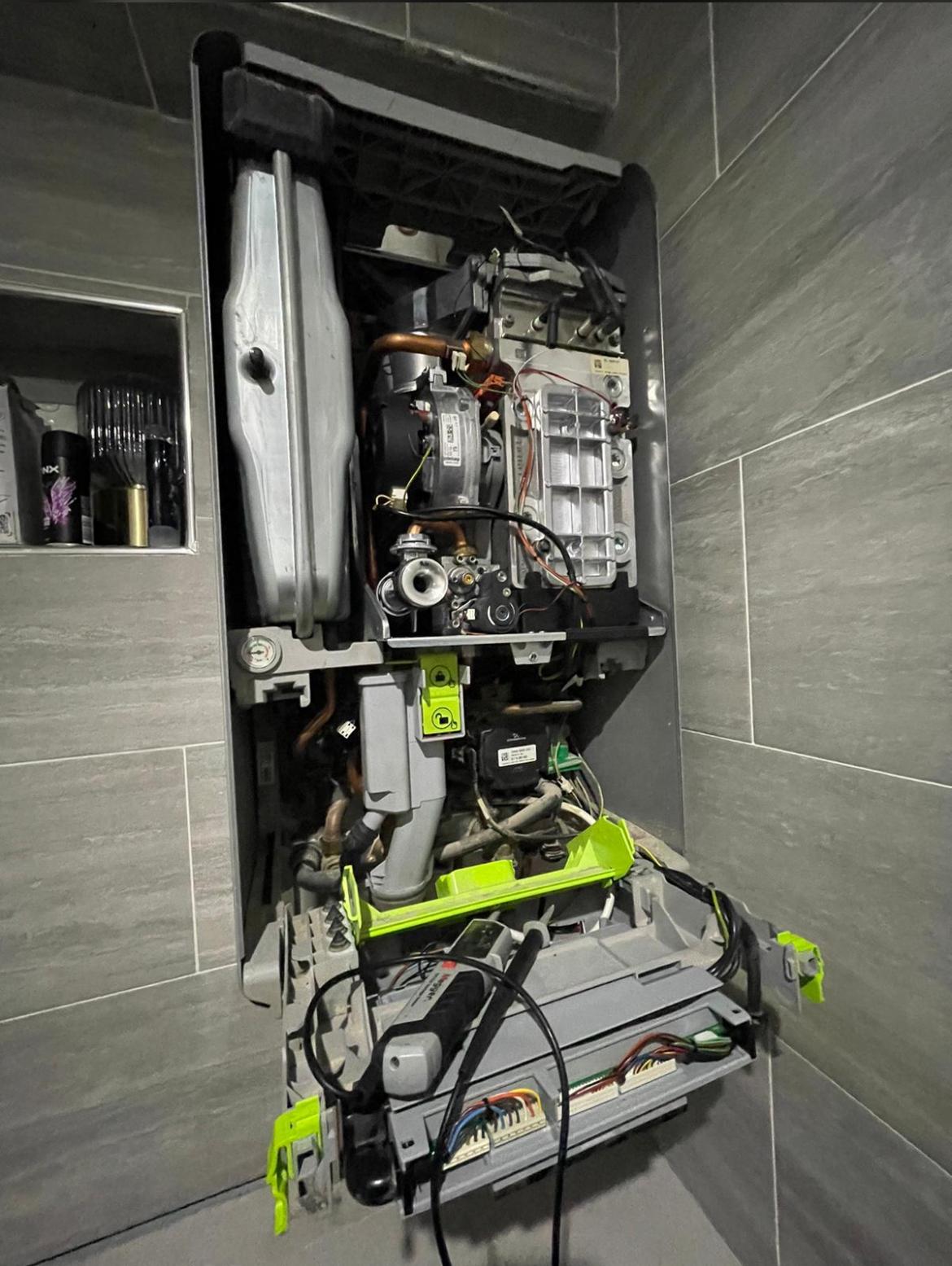 Condensing boiler service in progress with cover removed showing internal components