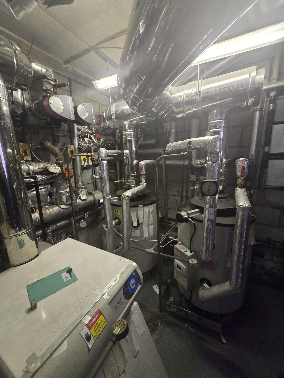 Large commercial plant room with industrial boilers, cylinders and insulated pipework