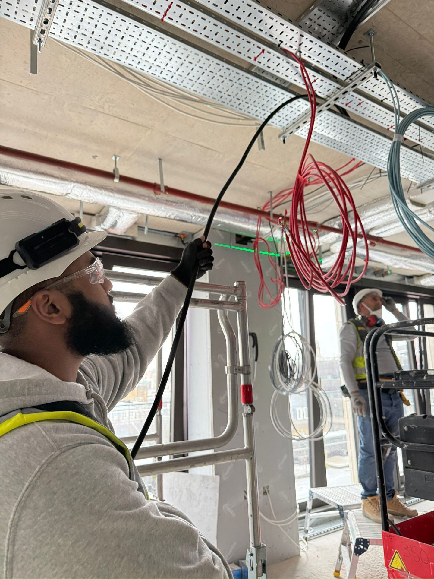 MAMOSS electrician pulling cables through containment on a London commercial project