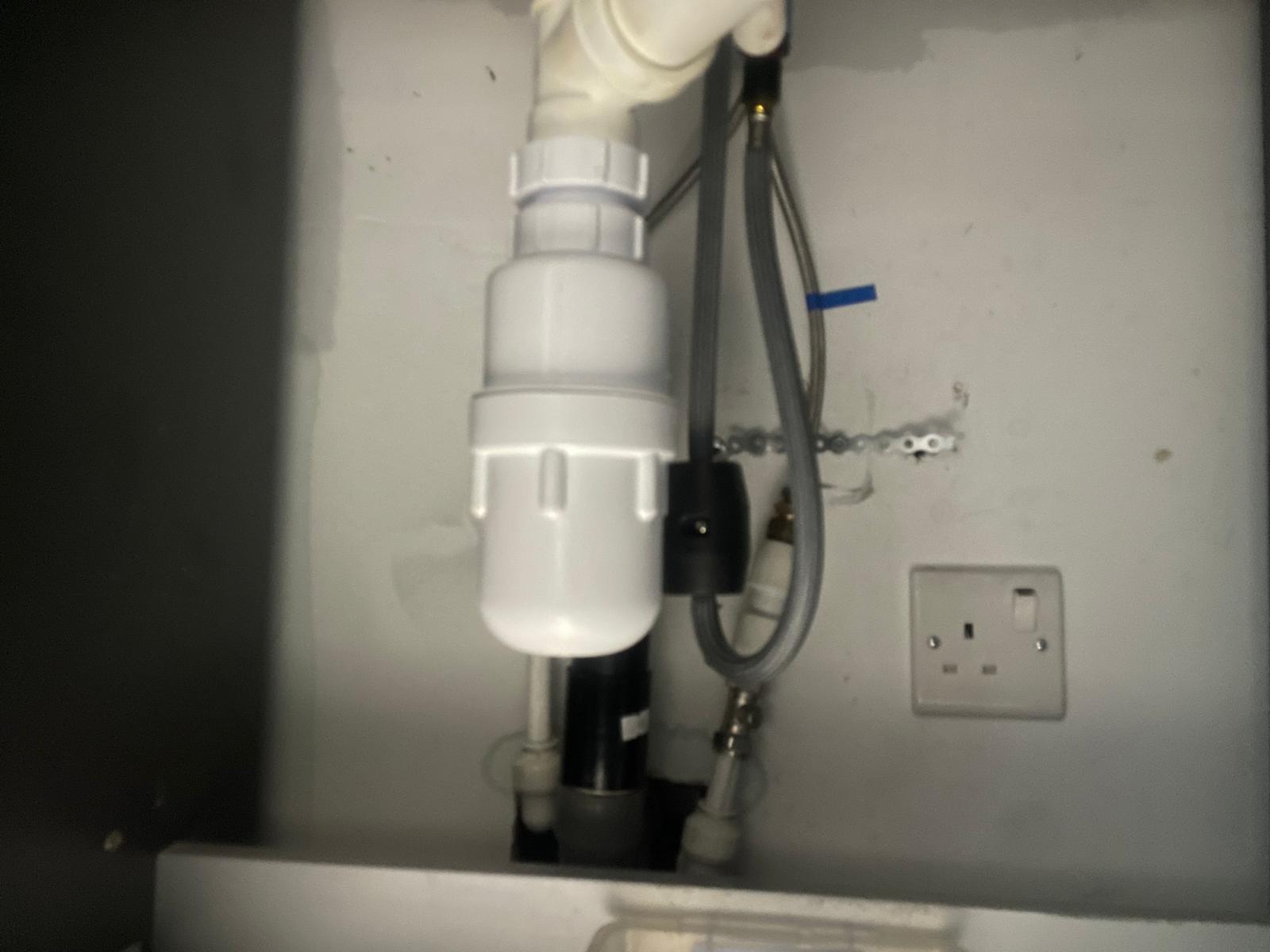 Under-sink plumbing waste trap and pipework installation in London kitchen