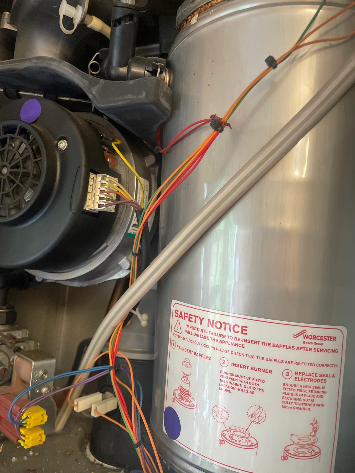 Close-up of Worcester boiler heat exchanger with safety notice label during annual service